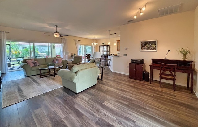 living room featuring ceiling fan with notable chandelier and dark hardwood / wood-style flooring