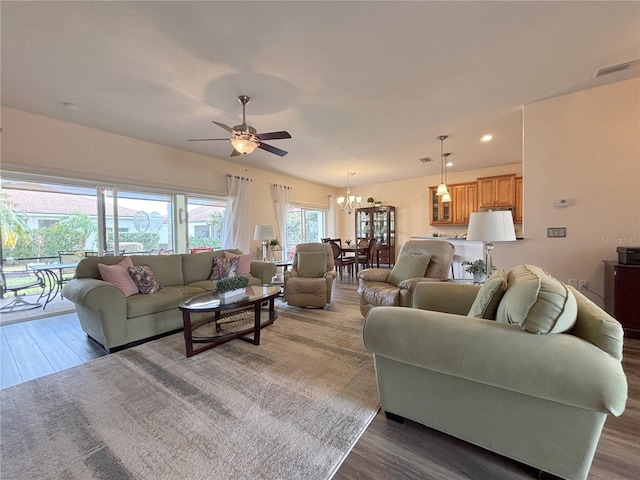 living room featuring dark hardwood / wood-style flooring and ceiling fan with notable chandelier