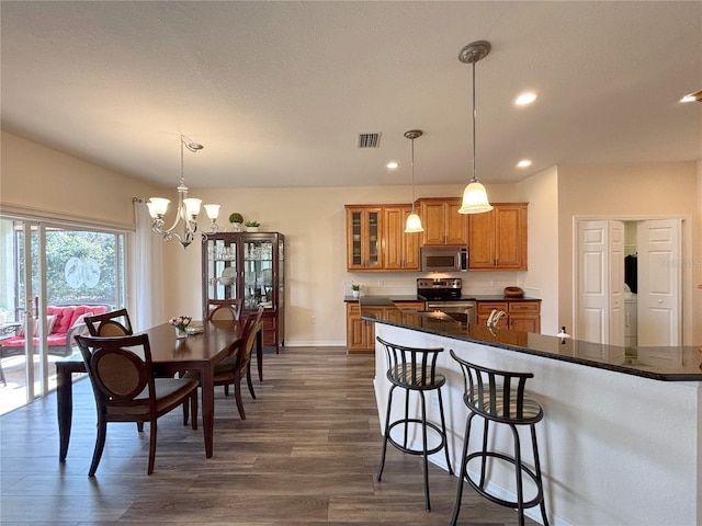 kitchen featuring pendant lighting, stainless steel appliances, dark hardwood / wood-style flooring, and a breakfast bar area