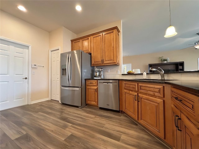 kitchen featuring pendant lighting, sink, dark wood-type flooring, ceiling fan, and appliances with stainless steel finishes