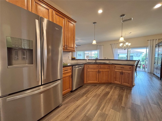 kitchen with sink, dark wood-type flooring, hanging light fixtures, stainless steel appliances, and kitchen peninsula