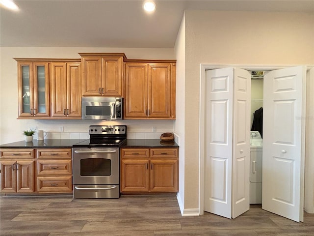 kitchen with stainless steel appliances, washer / dryer, and dark wood-type flooring