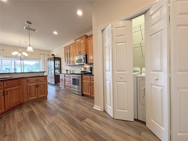 kitchen with pendant lighting, hardwood / wood-style flooring, washer and dryer, and appliances with stainless steel finishes