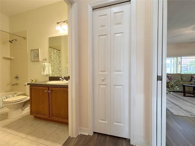 full bathroom with hardwood / wood-style flooring, vanity, shower / bath combo with shower curtain, and toilet