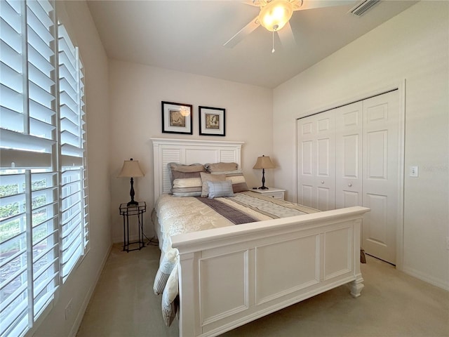 bedroom featuring light colored carpet, ceiling fan, and a closet