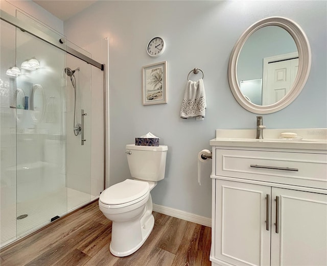 bathroom with vanity, toilet, a shower with shower door, and hardwood / wood-style floors