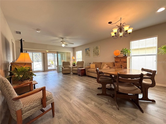 dining space with hardwood / wood-style floors and ceiling fan with notable chandelier