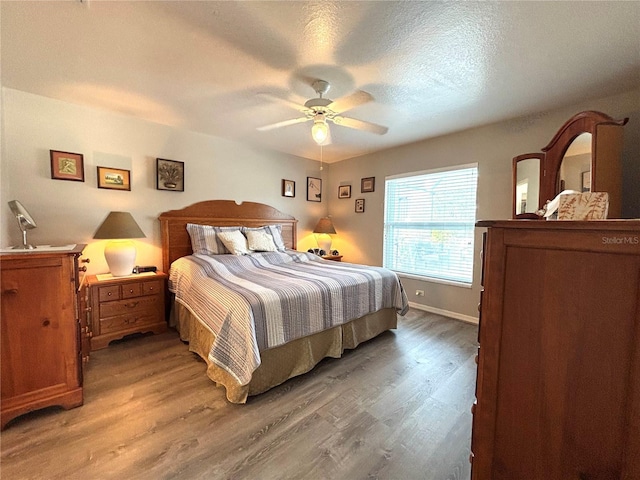 bedroom with ceiling fan, wood-type flooring, and a textured ceiling