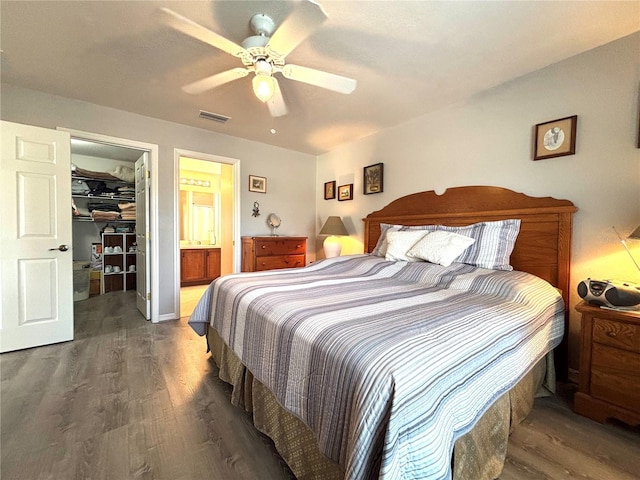 bedroom featuring connected bathroom, a spacious closet, dark hardwood / wood-style floors, a closet, and ceiling fan