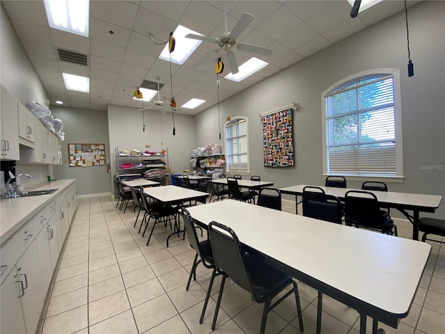 dining room with sink, light tile patterned floors, a drop ceiling, and ceiling fan