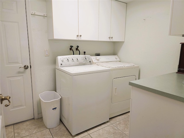 laundry room with cabinets, washer and clothes dryer, and light tile patterned floors