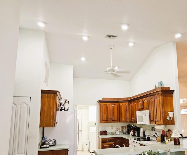 kitchen featuring high vaulted ceiling, washer / dryer, ceiling fan, kitchen peninsula, and white appliances