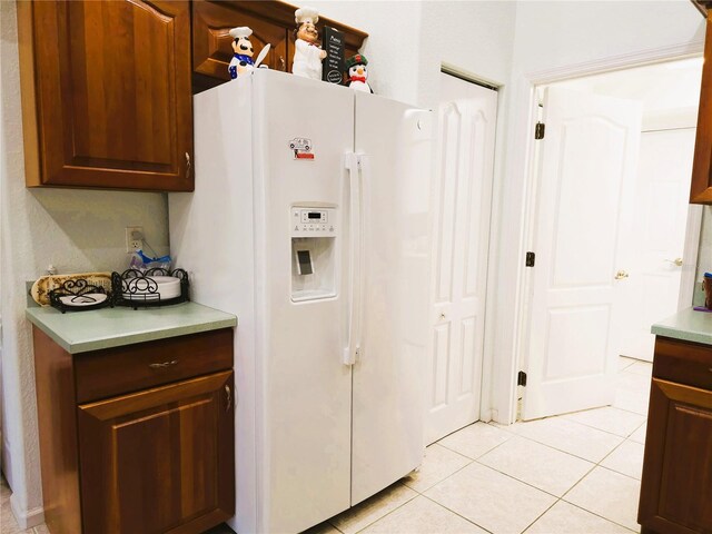 kitchen with white refrigerator with ice dispenser and light tile patterned flooring