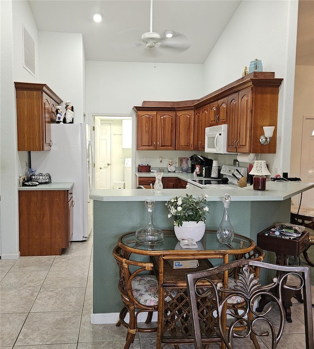 kitchen featuring washer / dryer, white appliances, light tile patterned floors, kitchen peninsula, and ceiling fan