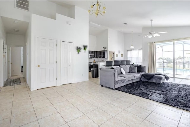 living room featuring light tile patterned floors, ceiling fan with notable chandelier, and high vaulted ceiling