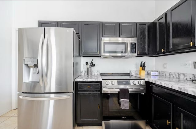 kitchen featuring light tile patterned flooring, stainless steel appliances, and light stone countertops