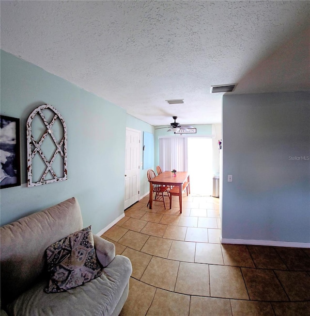 tiled living room featuring ceiling fan and a textured ceiling