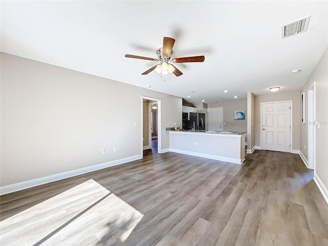 unfurnished living room featuring ceiling fan and light hardwood / wood-style flooring