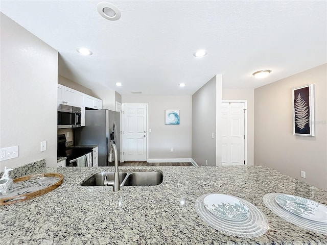 kitchen featuring appliances with stainless steel finishes, sink, white cabinets, and light stone counters