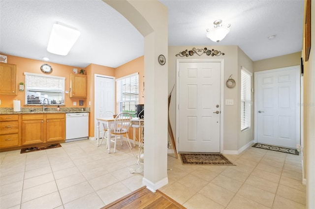 entryway with sink, light tile patterned floors, and a wealth of natural light