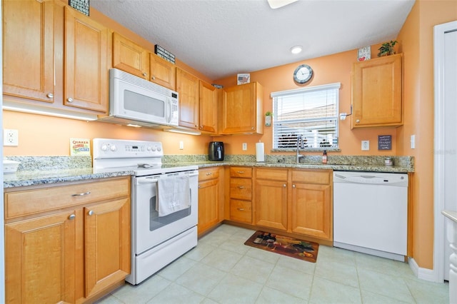 kitchen featuring white appliances, light stone countertops, sink, and a textured ceiling