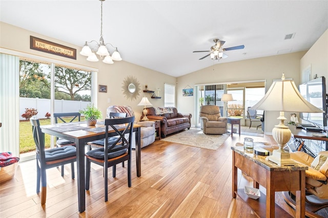 dining room with vaulted ceiling, ceiling fan with notable chandelier, and light hardwood / wood-style floors