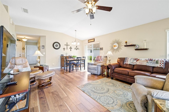 living room with ceiling fan with notable chandelier, light hardwood / wood-style flooring, and vaulted ceiling