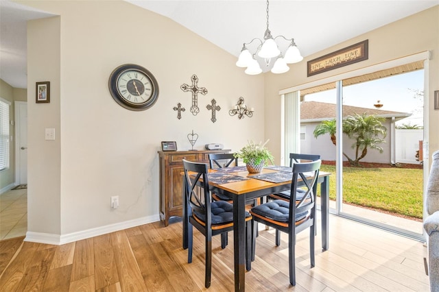 dining space with vaulted ceiling, a chandelier, and light wood-type flooring