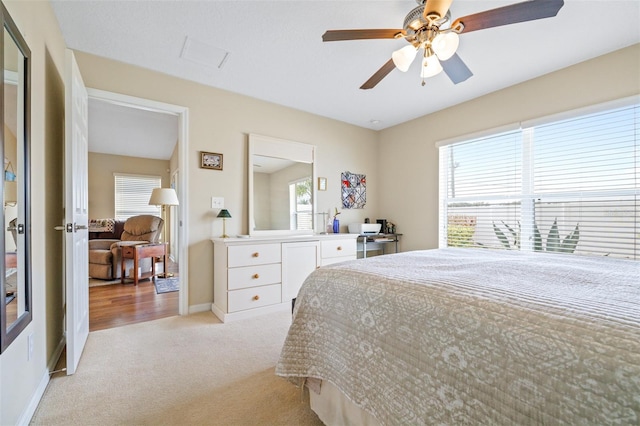 bedroom with ceiling fan, light carpet, and multiple windows