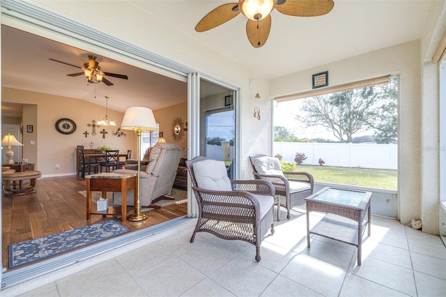 sunroom featuring ceiling fan with notable chandelier and vaulted ceiling