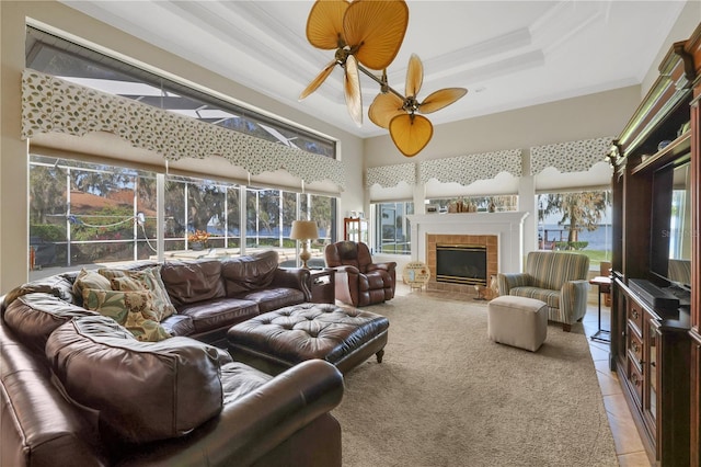 tiled living room featuring a tile fireplace, ornamental molding, a wealth of natural light, and a tray ceiling