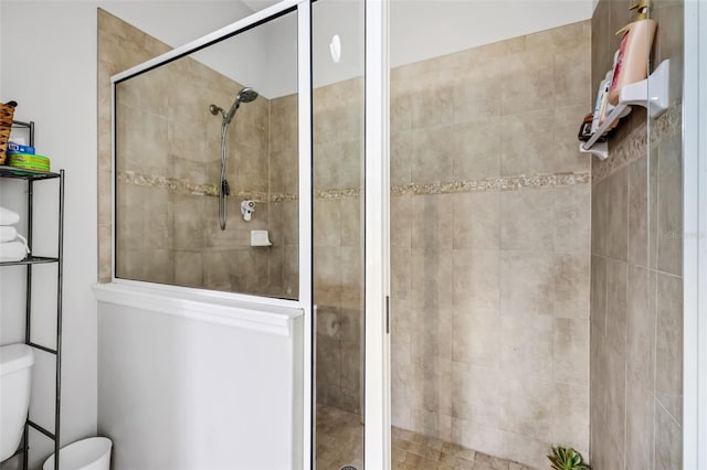 bathroom featuring tiled shower and toilet