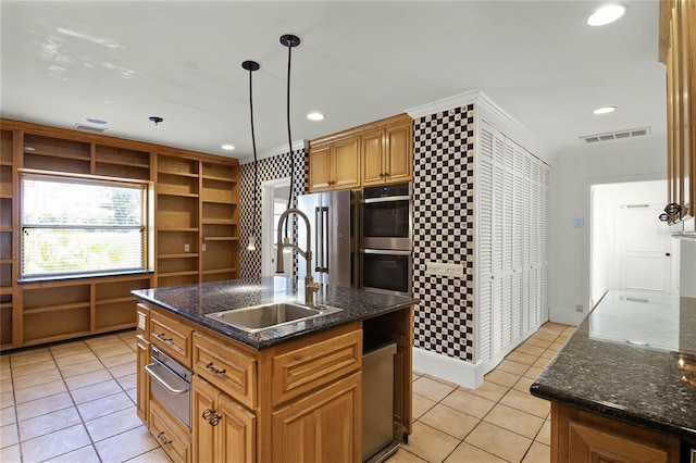 kitchen featuring pendant lighting, appliances with stainless steel finishes, sink, and an island with sink