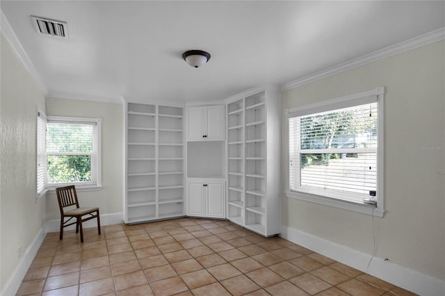 empty room with built in shelves, ornamental molding, and light tile patterned flooring