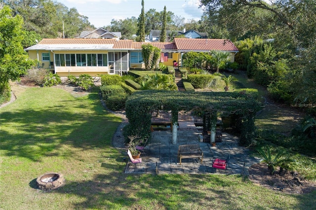 exterior space with a yard, a fire pit, a sunroom, and a patio