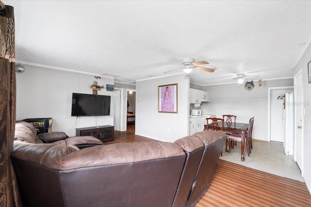 living room featuring ceiling fan, ornamental molding, and a textured ceiling