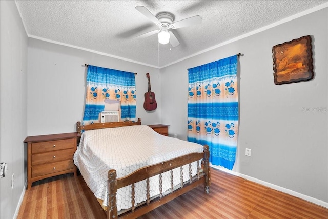 bedroom with wood-type flooring, ceiling fan, a textured ceiling, and crown molding