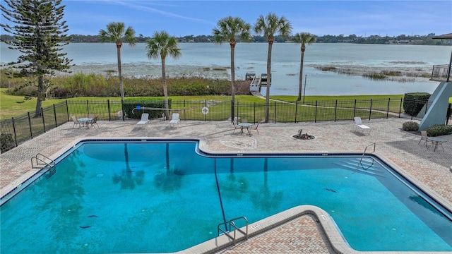 view of pool featuring a water view, a yard, and a patio