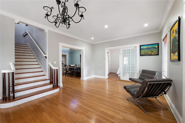 living area with a notable chandelier, ornamental molding, and light hardwood / wood-style floors