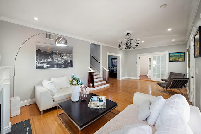 living room with ornamental molding, an inviting chandelier, and light hardwood / wood-style floors