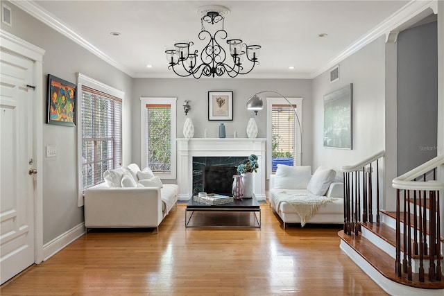 living area featuring ornamental molding, a chandelier, a fireplace, and light hardwood / wood-style floors