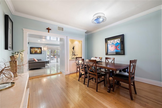 dining area with ornamental molding and light wood-type flooring