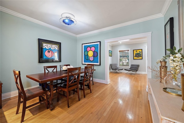dining space with crown molding and light hardwood / wood-style floors