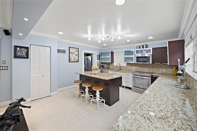 kitchen with a kitchen island, appliances with stainless steel finishes, sink, a breakfast bar area, and dark brown cabinets