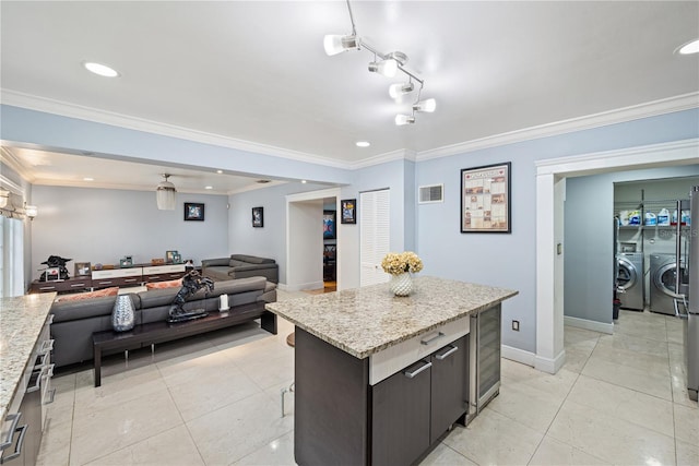kitchen with washer and dryer, light tile patterned floors, ornamental molding, and a center island