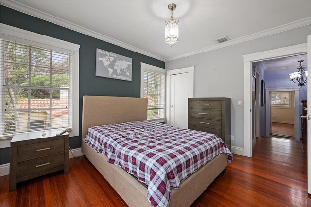 bedroom featuring crown molding, dark hardwood / wood-style flooring, an inviting chandelier, and a closet