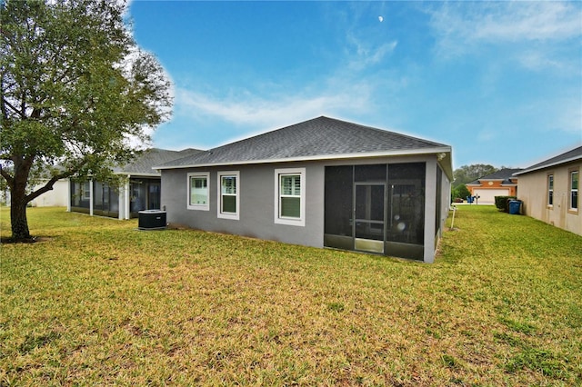 back of property featuring a sunroom, central air condition unit, and a lawn