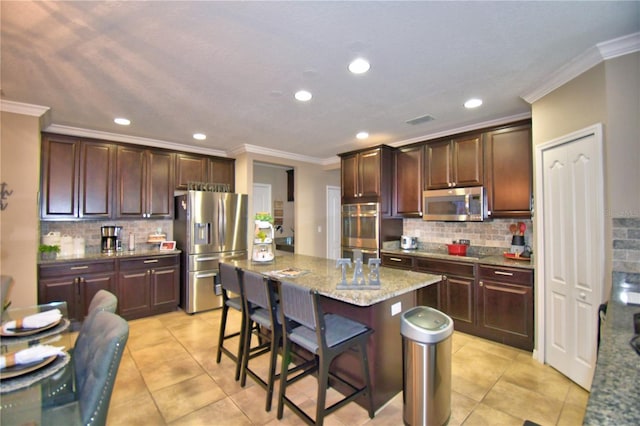 kitchen featuring a center island, light tile patterned floors, a kitchen breakfast bar, stainless steel appliances, and light stone countertops