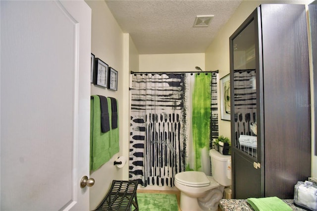 bathroom with a textured ceiling, toilet, and walk in shower