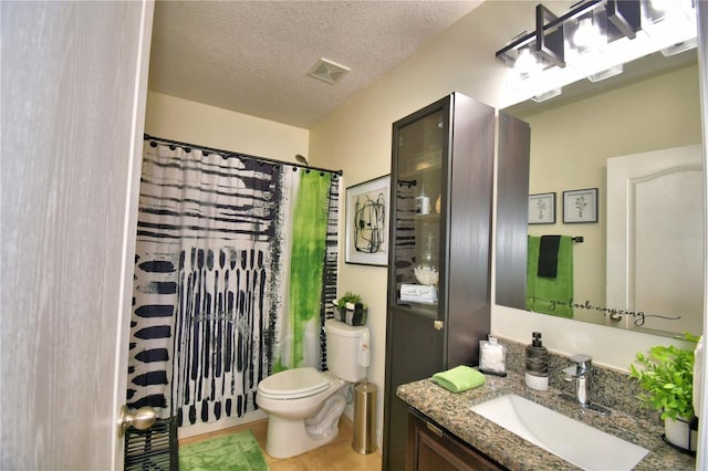 bathroom featuring tile patterned flooring, vanity, walk in shower, toilet, and a textured ceiling